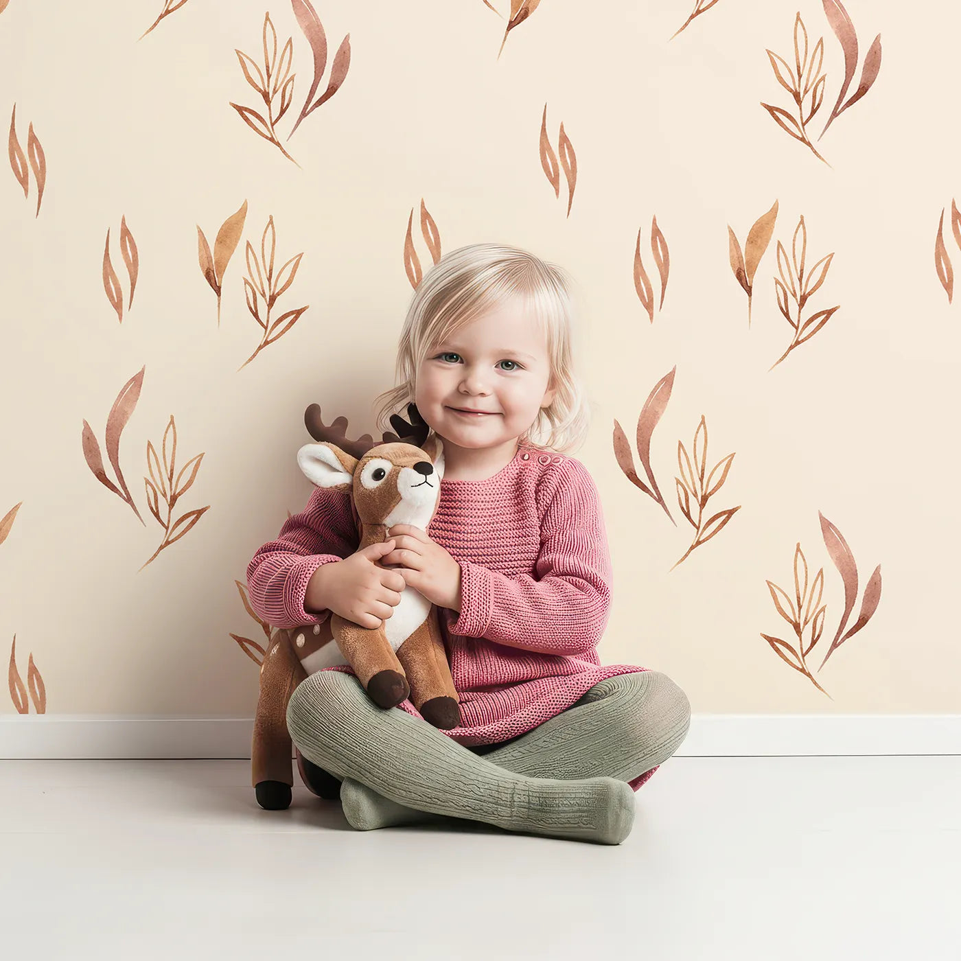 Lovely child standing in front of Whimsy Tots Rustling Meadow Sprigs Wallpaper in Sand with leaf, sprig, botanical, plant in design.
