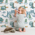 Lovely child standing in front of Whimsy Tots Ocean Pals Parade Wallpaper in White with whale, turtle, fish, octopus, jellyfish, sea dragon in design.