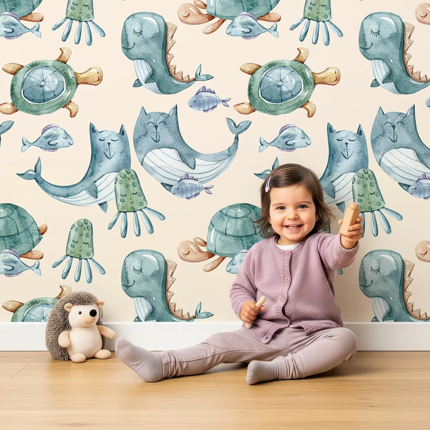 Lovely child standing in front of Whimsy Tots Ocean Pals Parade Wallpaper in Sand with whale, turtle, fish, octopus, jellyfish, sea dragon in design.