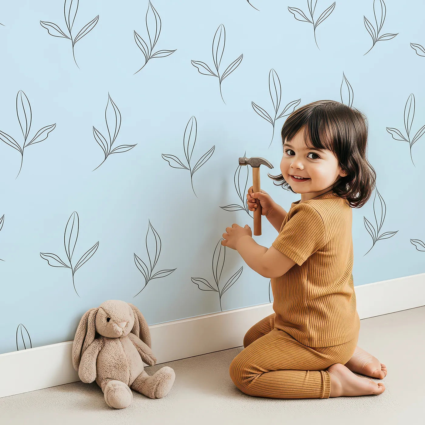 Lovely child standing in front of Whimsy Tots Whispering Leaflines Wallpaper in Blue with leaf, sprig, botanical, line art in design.
