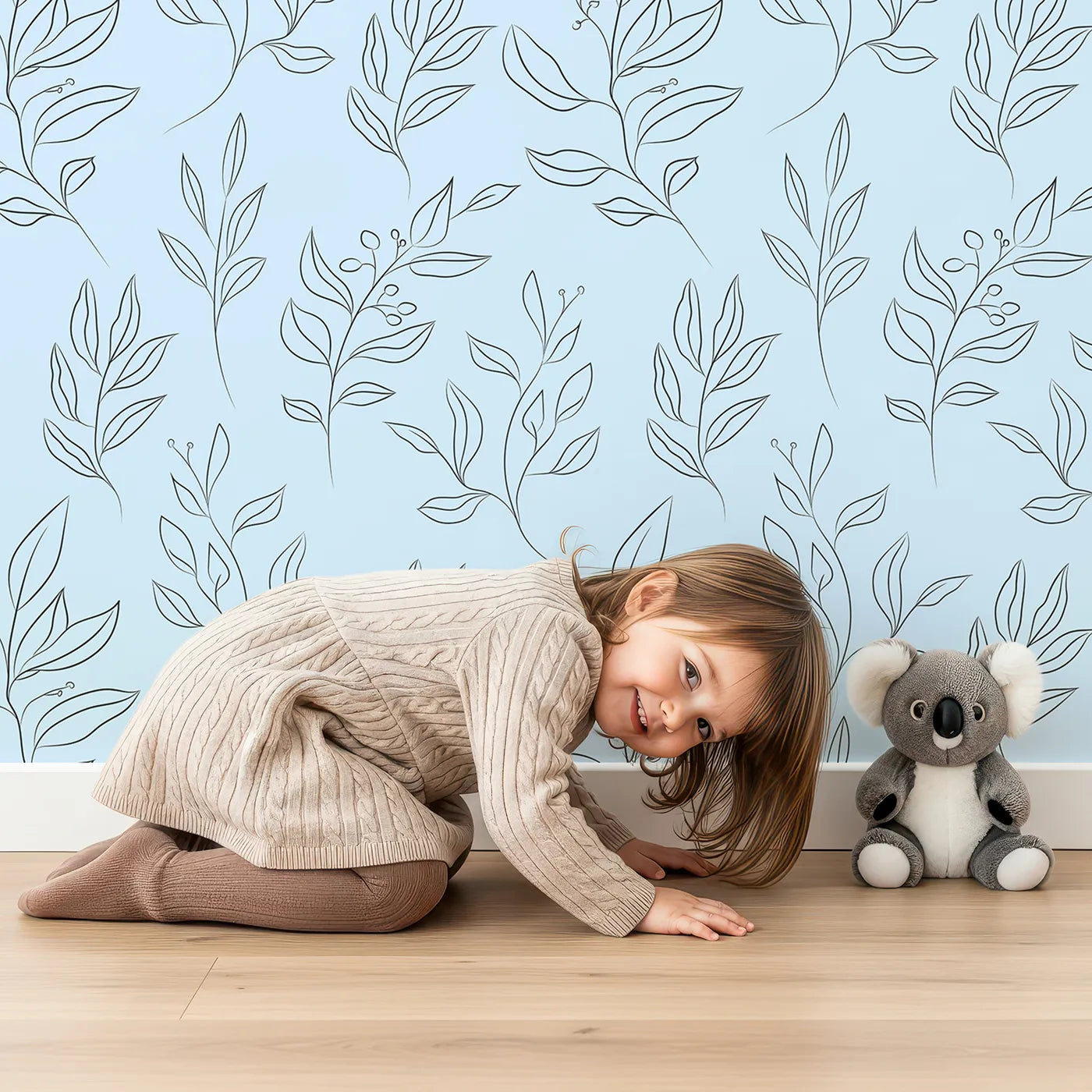 Lovely child standing in front of Whimsy Tots Wild Leafline Garden Wallpaper in Blue with leaf, botanical, sprig, berry, line art in design.