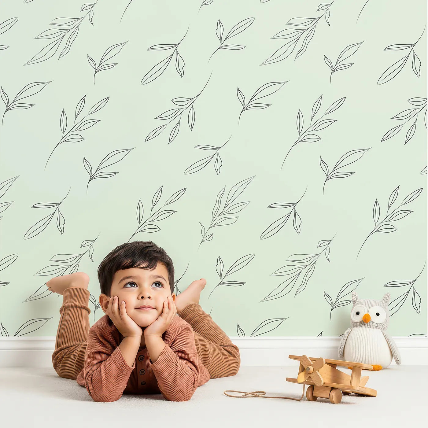 Lovely child standing in front of Whimsy Tots Leaf Outline Symphony Wallpaper in Mint Green with leaf, branch, botanical, outline in design.