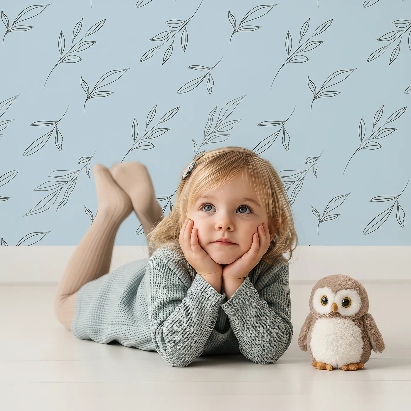Lovely child standing in front of Whimsy Tots Leaf Outline Symphony Wallpaper in Sky Blue with leaf, branch, botanical, outline in design.