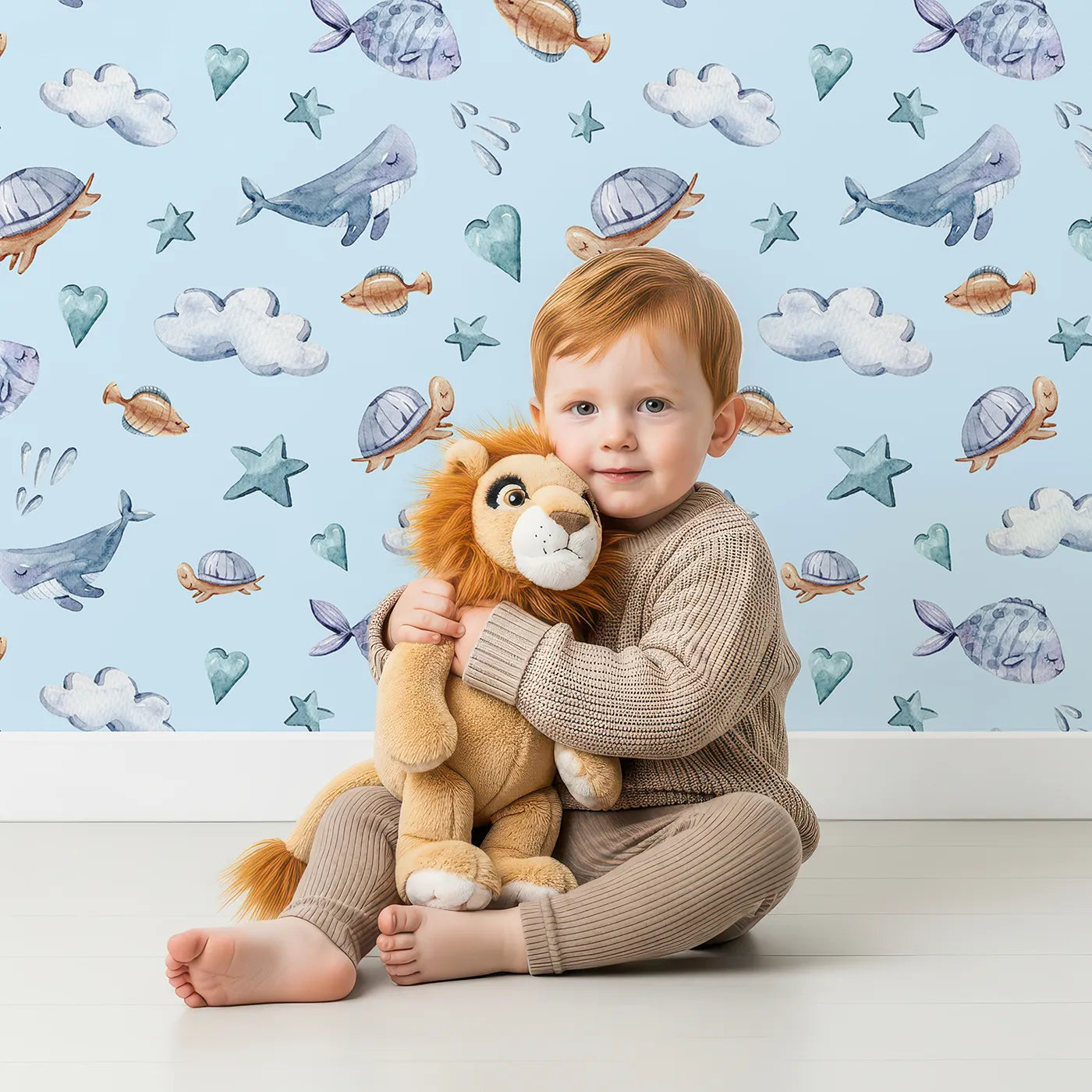 Lovely child standing in front of Whimsy Tots Sleepy Sea Sky Wallpaper in Blue with whale, turtle, fish, cloud, star, heart in design.