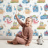 Lovely child standing in front of Whimsy Tots Undersea Island Adventure Wallpaper in White with whale, turtle, submarine, starfish, bottle, island, sea creature in design.