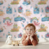 Lovely child standing in front of Whimsy Tots Undersea Island Adventure Wallpaper in Blush Pink with whale, turtle, dolphin, octopus, fish, starfish, shrimp, submarine, bottle, island in design.