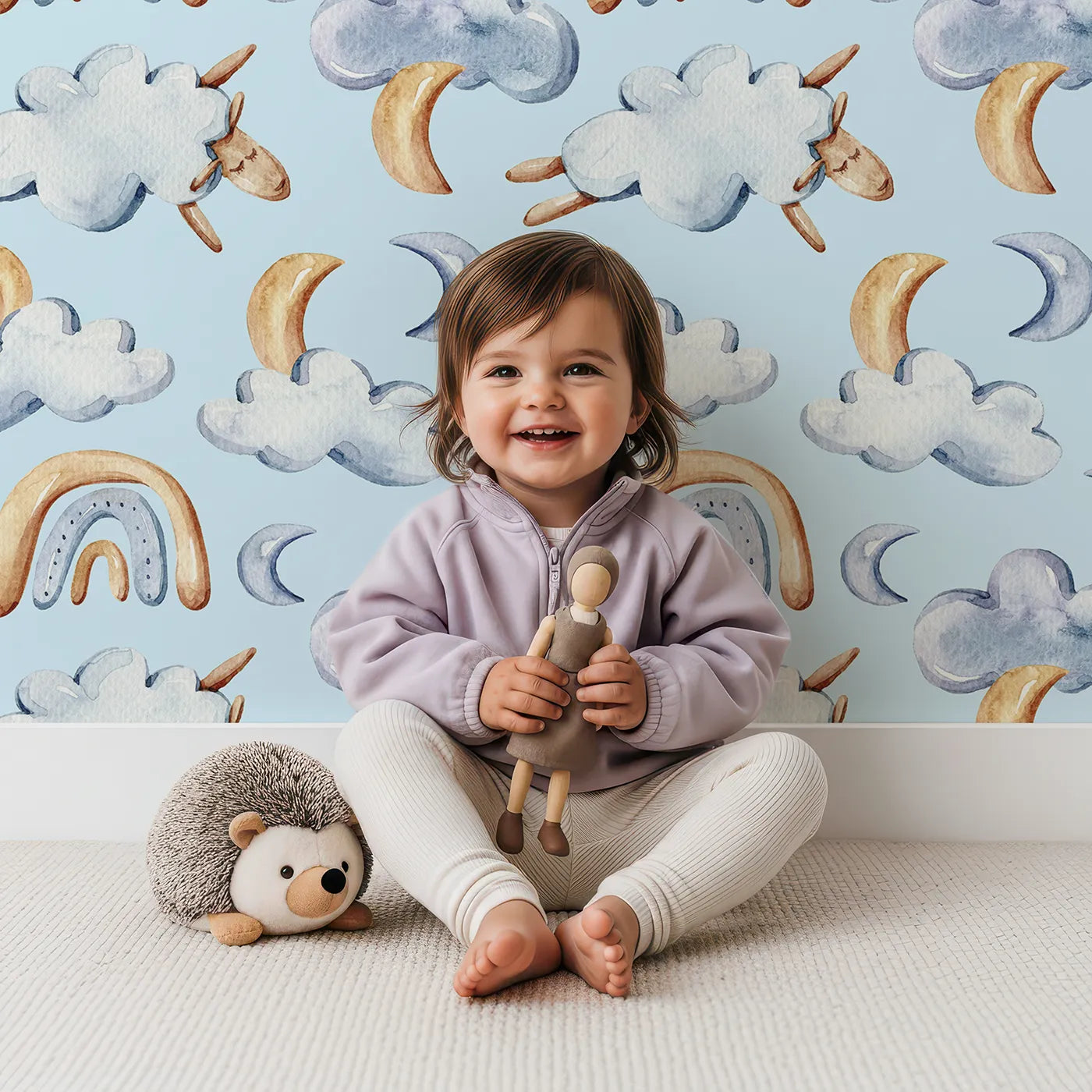Lovely child standing in front of Whimsy Tots Sleepy Cloud Parade Wallpaper in Blue with cloud, moon, sheep, rainbow, star in design.
