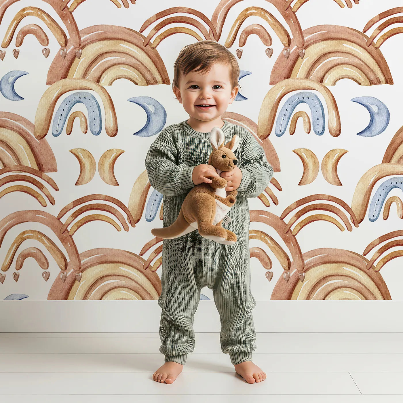 Lovely child standing in front of Whimsy Tots Boho Rainbow Night Wallpaper in White with rainbow, moon, heart, arch in design.