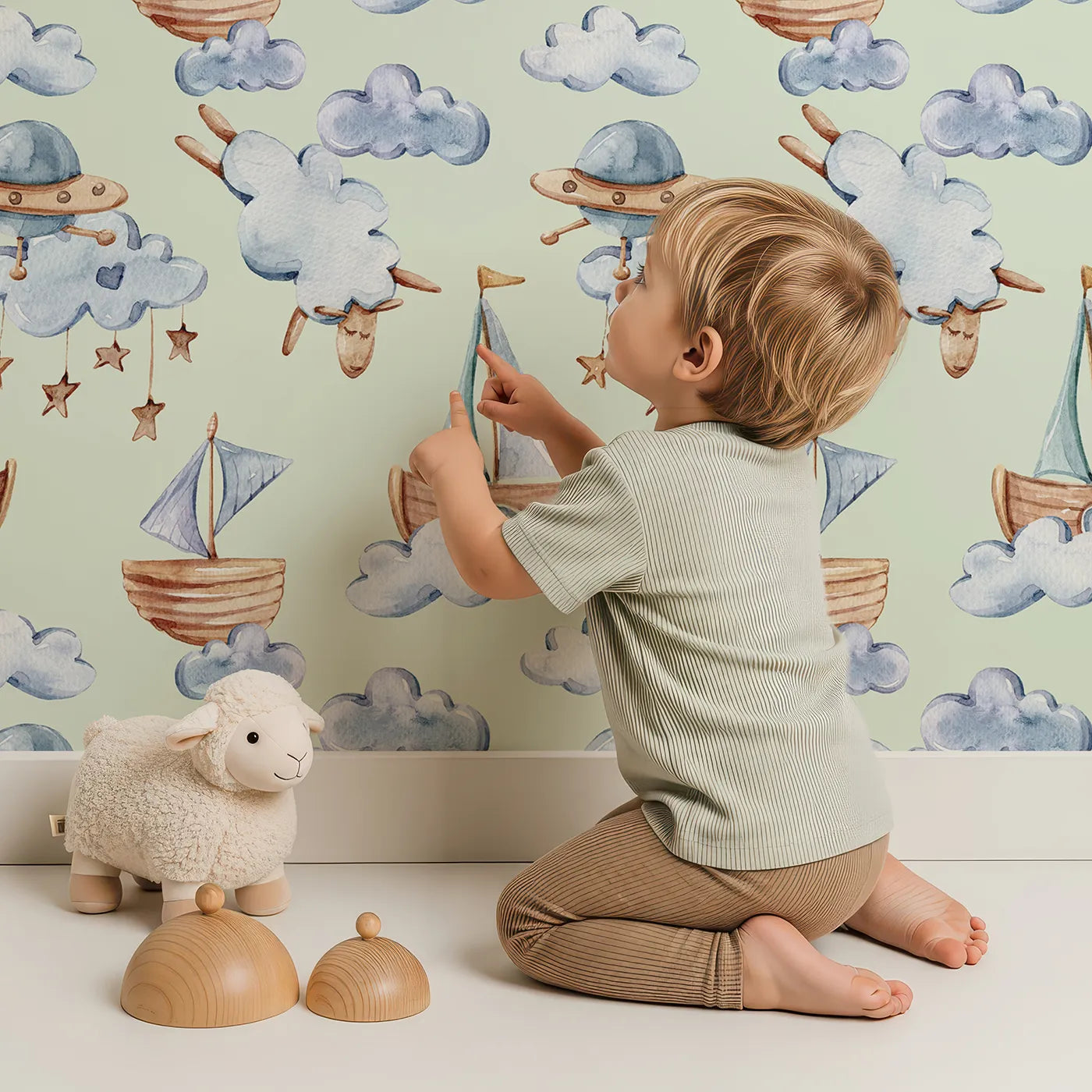 Lovely child standing in front of Whimsy Tots Counting Clouds and Sailing Dreams Wallpaper in Mint Green with sheep, boat, cloud, star, mobile in design.