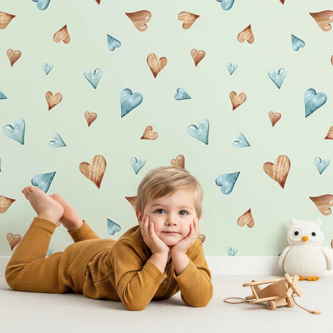 Lovely child standing in front of Whimsy Tots Heartful Whimsy Wallpaper in Mint Green with heartful, whimsy, wallpaper in design.