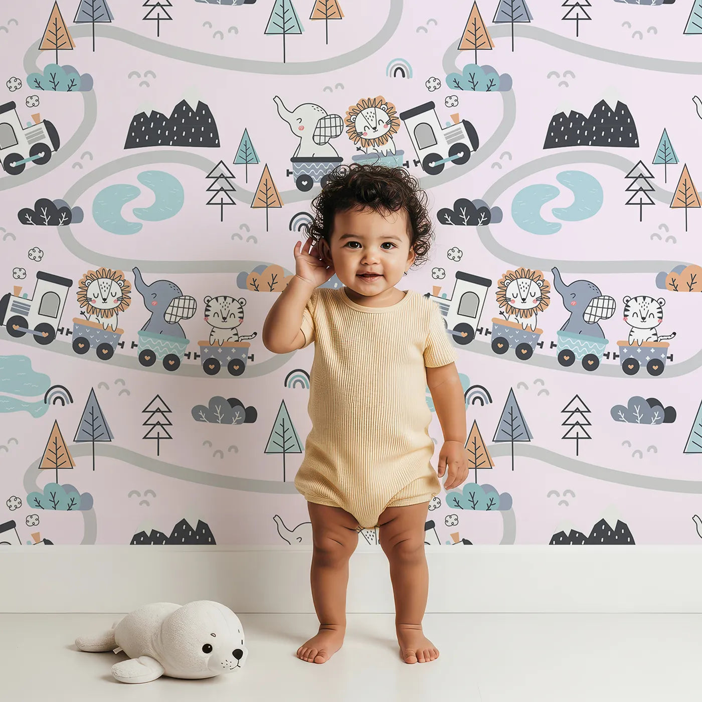 Lovely child standing in front of Whimsy Tots Animal Train Adventure Wallpaper in Blush Pink with train, lion, elephant, tiger, rainbow, mountain, tree in design.