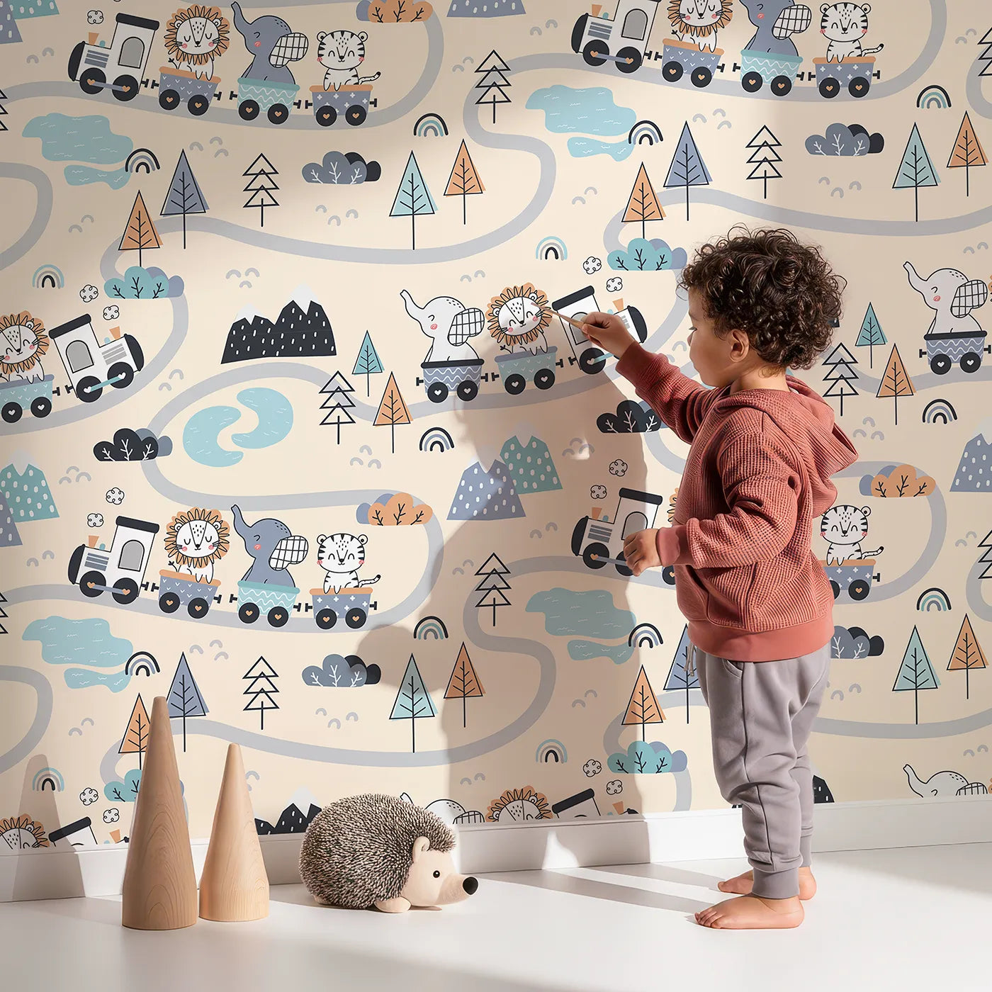Lovely child standing in front of Whimsy Tots Animal Train Adventure Wallpaper in Sand with train, lion, elephant, tiger, rainbow, tree, mountain in design.