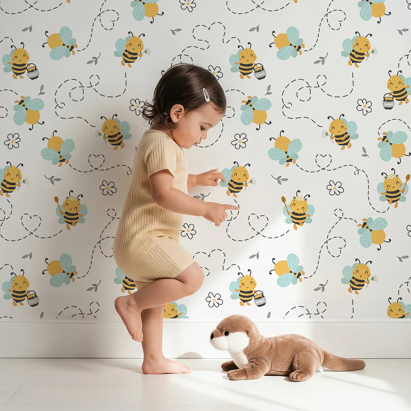 Lovely child standing in front of Whimsy Tots Busy Bees at Play Wallpaper in White with bee, flower, honey, leaf in design.
