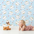 Lovely child standing in front of Whimsy Tots Royal Kitty Wink Wallpaper in Blue with cat, heart, crown in design.