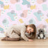Lovely child standing in front of Whimsy Tots Bunny Bounce Abstract Wallpaper in Blush Pink with bunny, blob, heart, texture in design.