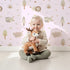 Lovely child standing in front of Whimsy Tots Sleepy Safari Snuggles Wallpaper in Lilac Lavender with elephant, zebra, lion, giraffe, hippo, tree, flower in design.
