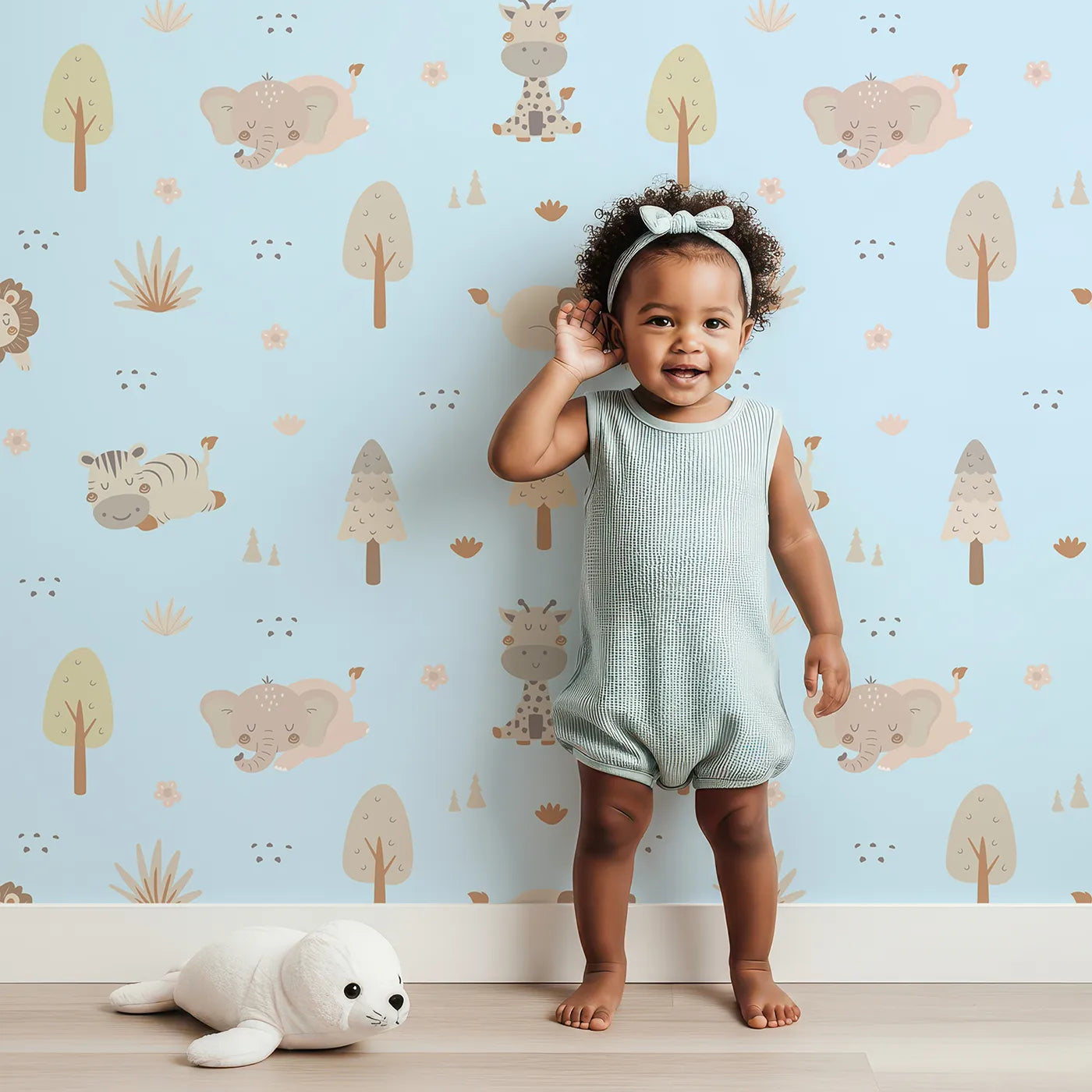 Lovely child standing in front of Whimsy Tots Sleepy Safari Snuggles Wallpaper in Sky Blue with elephant, zebra, lion, giraffe, hippo, tree, flower in design.