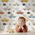 Lovely child standing in front of Whimsy Tots Animal Drivers Parade Wallpaper in White Grid with car, lion, elephant, koala, tiger, crocodile, traffic cone, cloud in design.