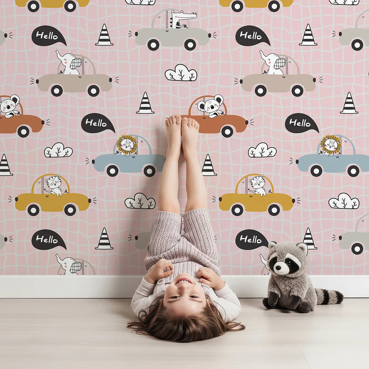 Lovely child standing in front of Whimsy Tots Animal Drivers Parade Wallpaper in Pink Grid with car, lion, elephant, koala, tiger, crocodile, traffic cone, cloud in design.