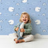 Lovely child standing in front of Whimsy Tots Sleepy Meadow Parade Wallpaper in Sky Blue with sheep, rainbow, cloud, star in design.