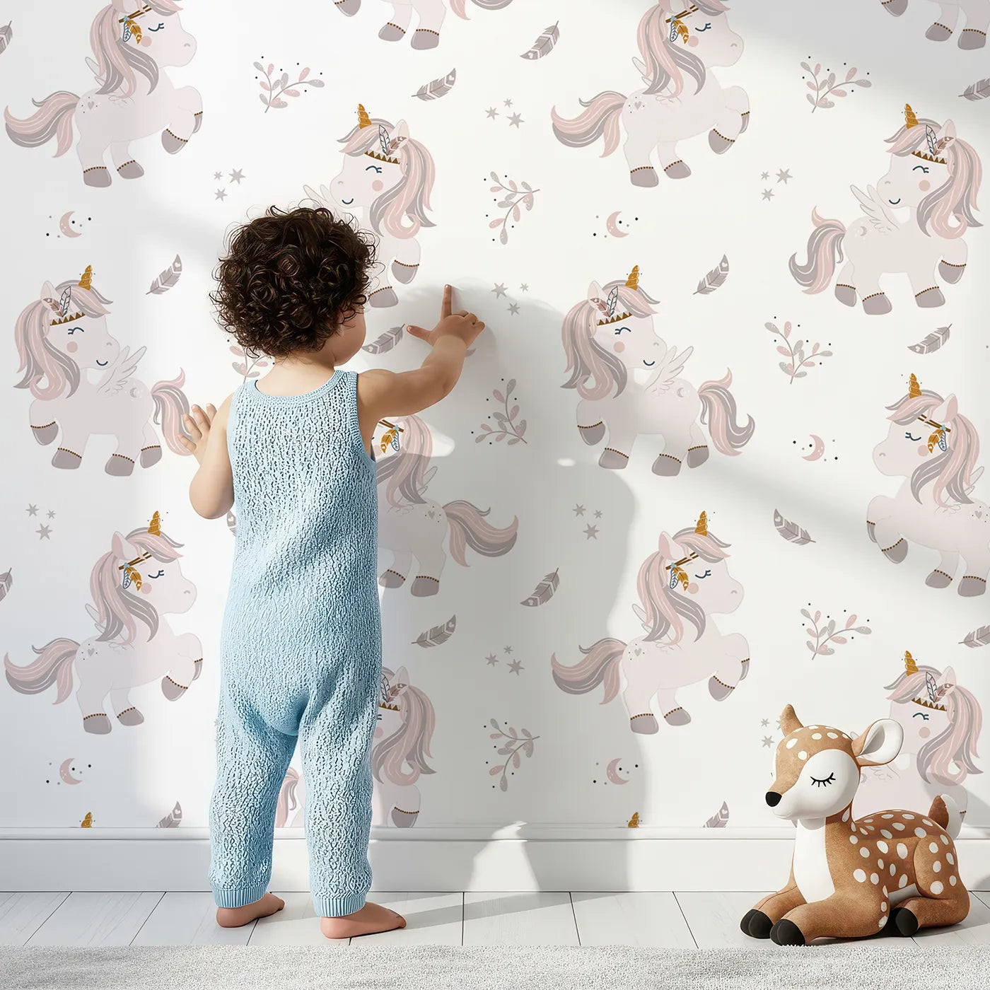 Lovely child standing in front of Whimsy Tots Feathered Daydream Unicorn Wallpaper in White with unicorn, feather, moon, star, leaf in design.