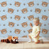 Lovely child standing in front of Whimsy Tots Tiger Grid Giggles Wallpaper in Blue with tiger, paw, grid in design.