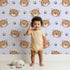 Lovely child standing in front of Whimsy Tots Tiger Grid Giggles Wallpaper in Lilac Lavender with tiger, paw, grid in design.