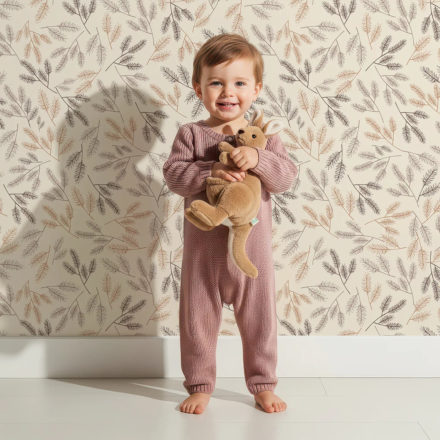 Lovely child standing in front of Whimsy Tots Whispering Ferns Wallpaper in Sandstone with fern, leaf, branch, foliage in design.