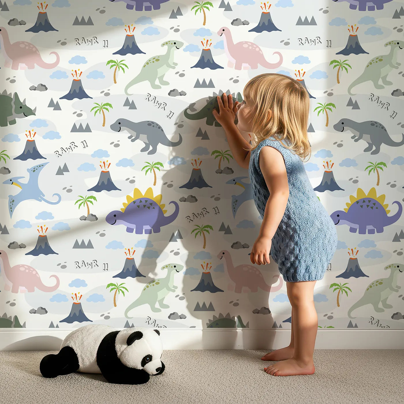 Lovely child standing in front of Whimsy Tots Rawr-some Dino Land Wallpaper in White with dinosaur, volcano, cloud, palm tree, mountain in design.