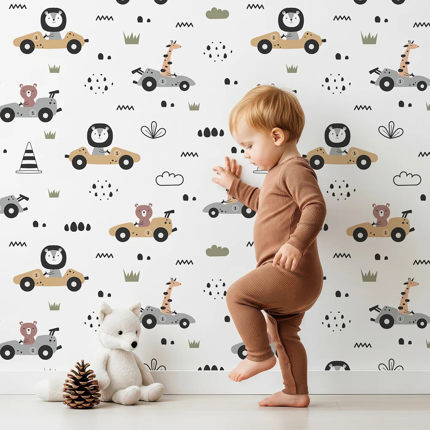 Lovely child standing in front of Whimsy Tots Safari Racers Parade Wallpaper in White with lion, giraffe, bear, car, wheel, road in design.