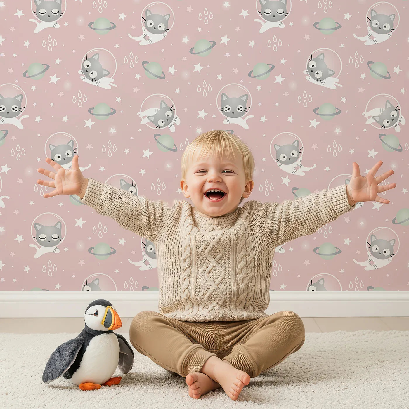 Lovely child standing in front of Whimsy Tots Space Kitty Drift Wallpaper in Blush Pink with cat, astronaut, planet, star, space in design.