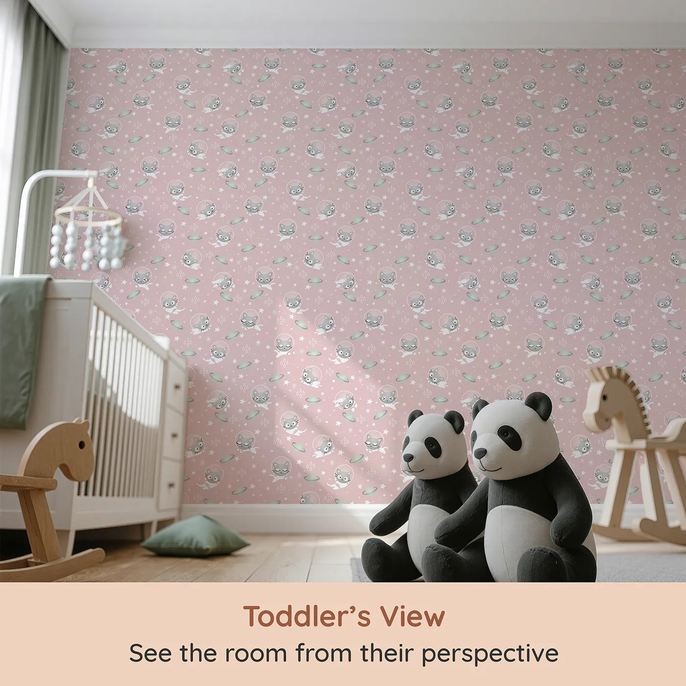 Whimsy Tots Space Kitty Drift Wallpaper in Blush Pink (W3480B) from your child's view.Astronaut cats drift across a gentle pink sky of stars and planets.