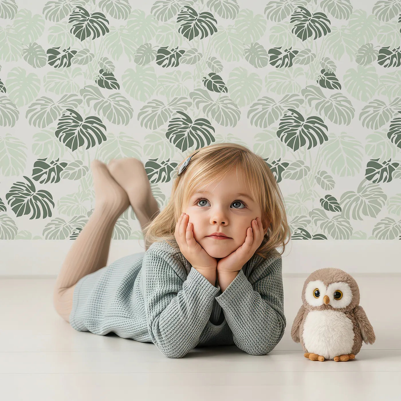 Lovely child standing in front of Whimsy Tots Monstera Jungle Wallpaper in Mint Mist Green with leaf, monstera, jungle, foliage in design.
