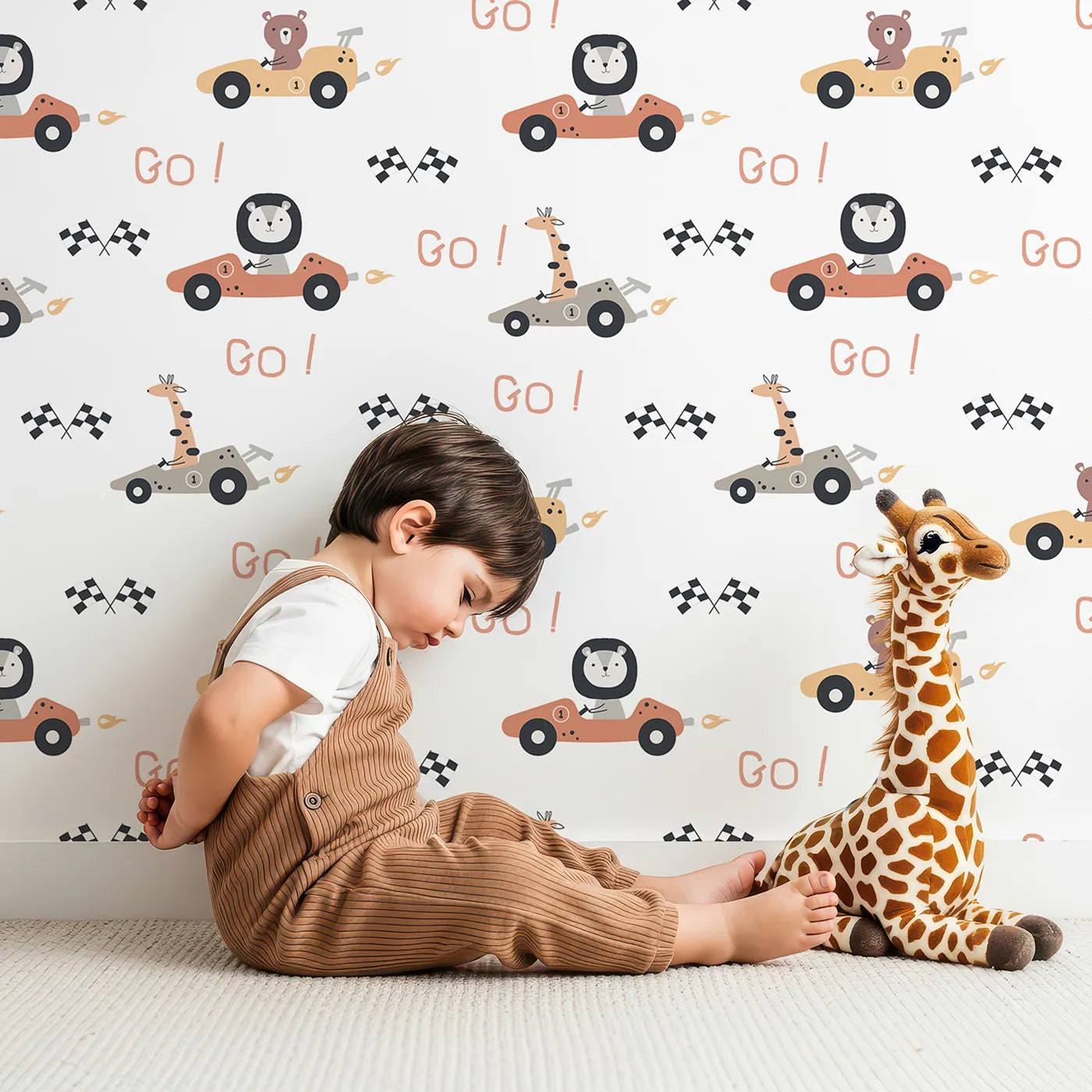Lovely child standing in front of Whimsy Tots Animal Racers Wallpaper in Soft Neutrals with giraffe, bear, lion, car, racecar, flag in design.