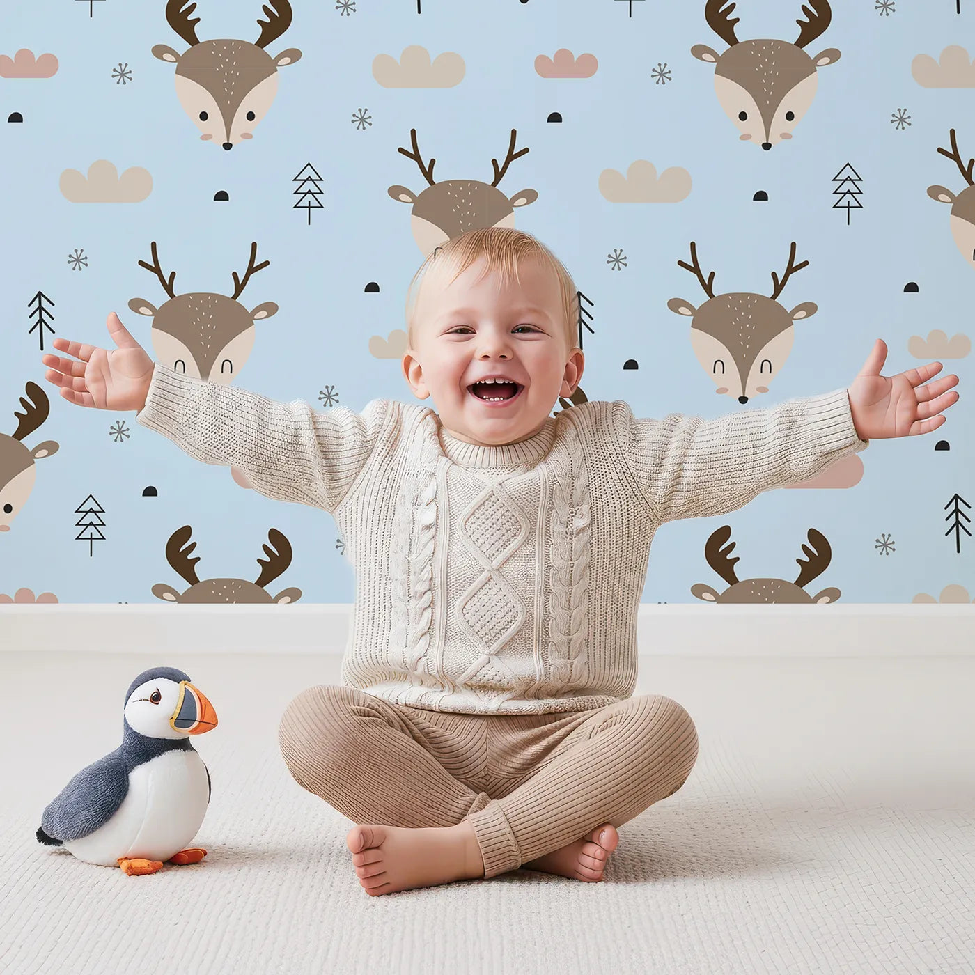 Lovely child standing in front of Whimsy Tots Woodland Deer Wallpaper in Sky Blue with deer, cloud, tree, snowflake in design.