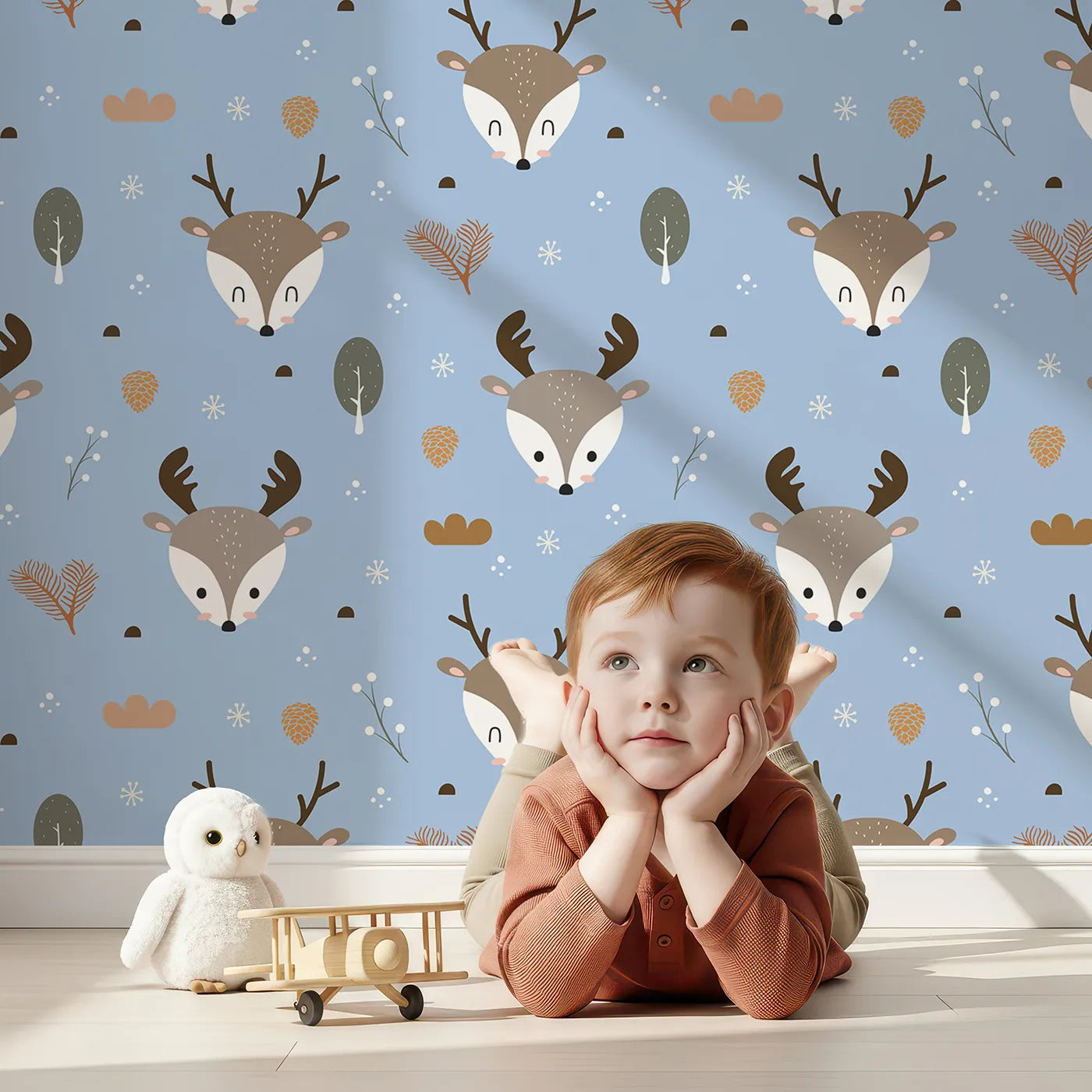 Lovely child standing in front of Whimsy Tots Forest Forager Deer Wallpaper in Sky Blue with deer, pinecone, tree, snowflake, berry in design.