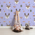 Lovely child standing in front of Whimsy Tots Forest Forager Deer Wallpaper in Lavender Mist with deer, pinecone, tree, snowflake, berry in design.