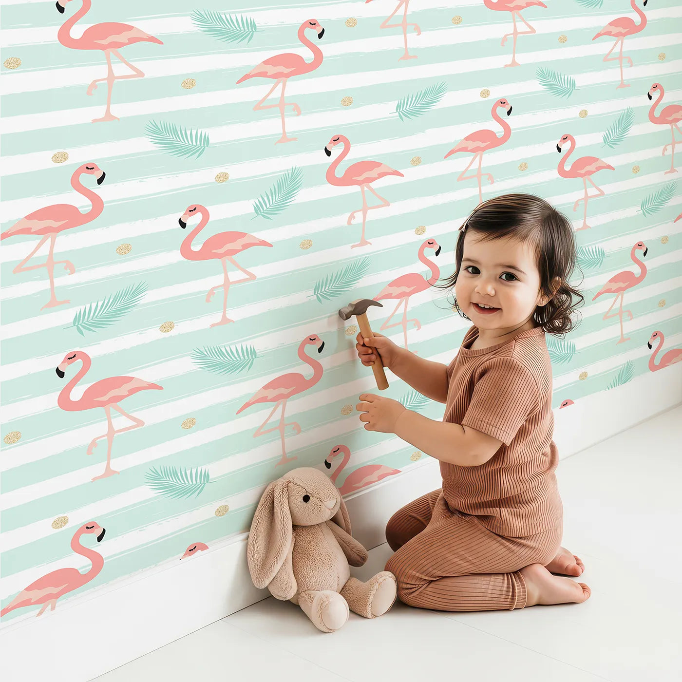 Lovely child standing in front of Whimsy Tots Flamingo Palm Parade Wallpaper in Mint Green with flamingo, palm, stripe, dot, bird in design.