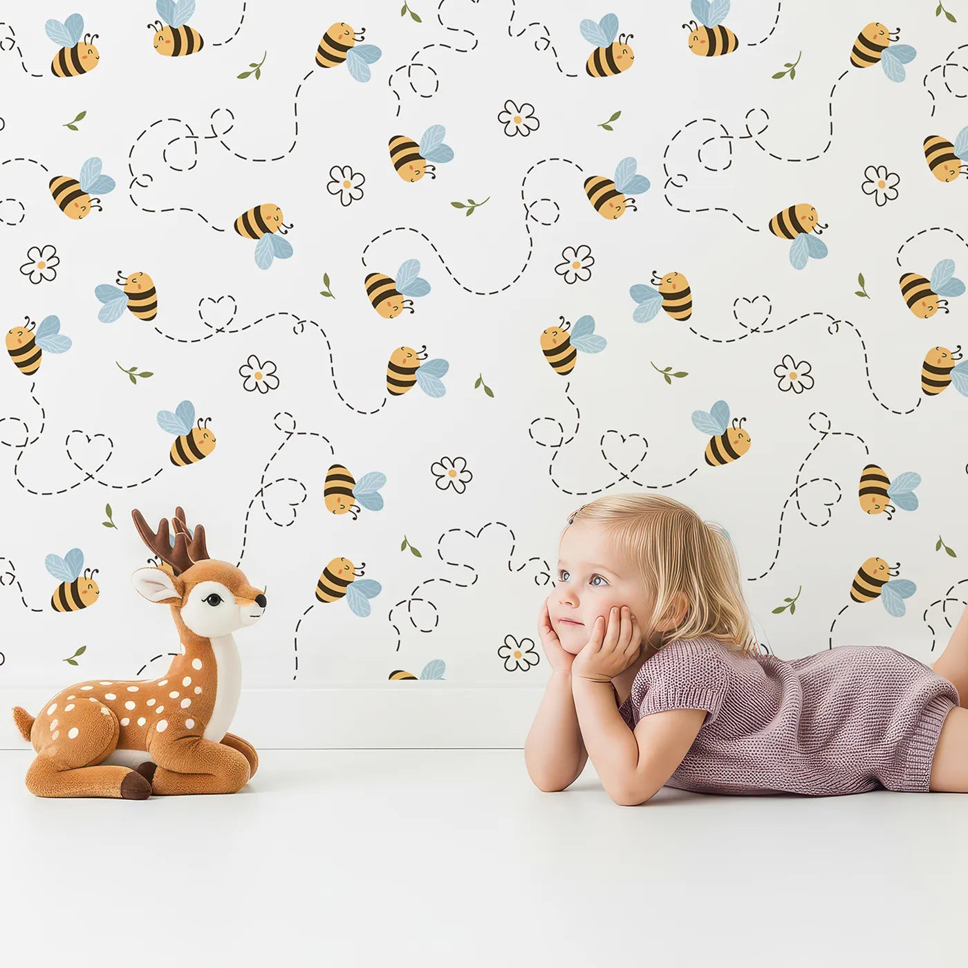 Lovely child standing in front of Whimsy Tots Busy Bee Trail Wallpaper in Bright White with bee, flower, leaf, heart, trail in design.