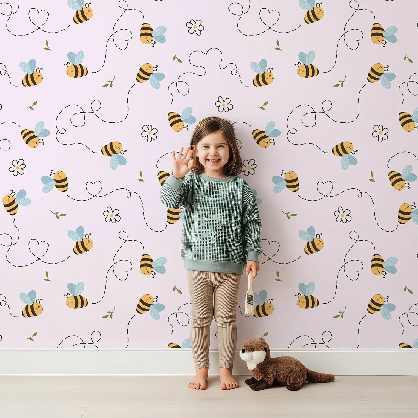 Lovely child standing in front of Whimsy Tots Busy Bee Trail Wallpaper in Blush Pink with bee, flower, leaf, heart, trail in design.