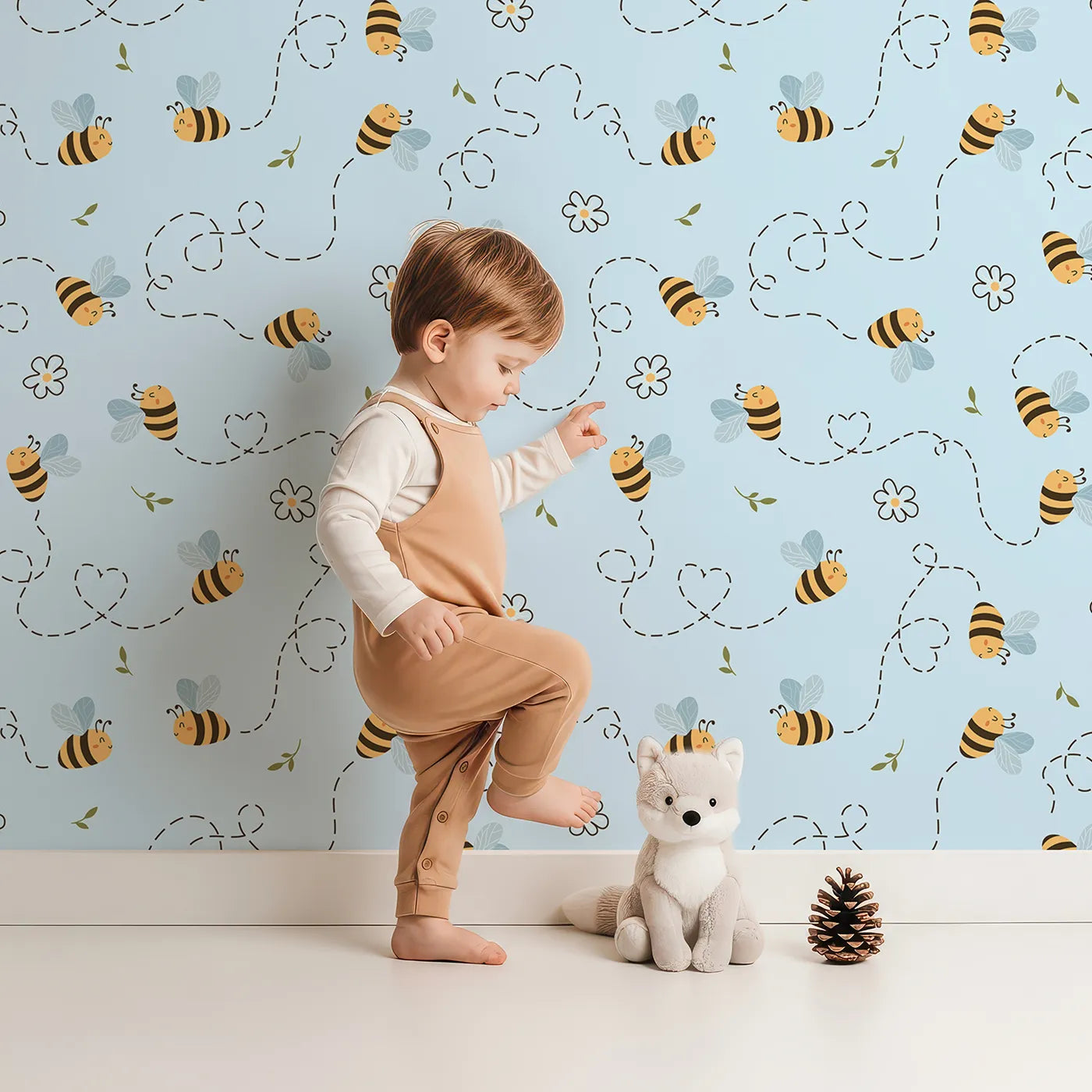 Lovely child standing in front of Whimsy Tots Busy Bee Trail Wallpaper in Sky Blue with bee, flower, leaf, heart, trail in design.
